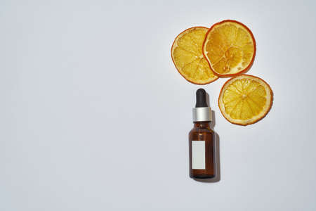 Pipette bottle filled with care oil next to orangeの写真素材