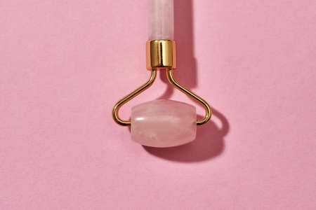 Close up shot of Rose quartz facial massage roller isolated over pink backgroundの写真素材