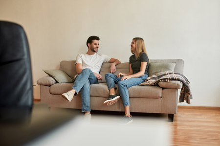 young couple sits on sofa and has a conversation