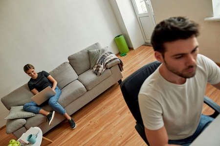 Picture of a young couple working together in the living room