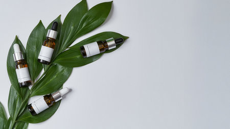 Glass bottles with cosmetological oils lying on leafの写真素材