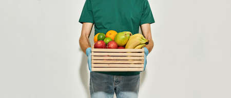 Wooden box with fruits in hands of courierの写真素材