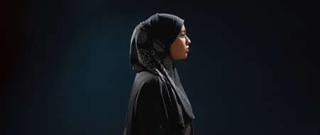 Profile of young arabian woman in hijab standing sidewaysの写真素材