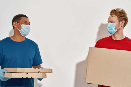 Multiracial postmen holding boxes on white backgroundの写真素材