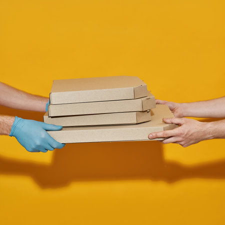 Hands of courier in protective gloves giving pizza boxesの写真素材