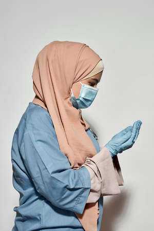 Young arabian woman doctor in facial mask posing sidewaysの写真素材