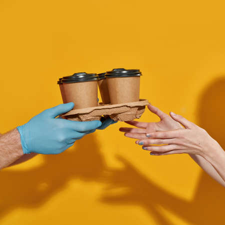 Deliveryman wearing rubber gloves giving coffee cups