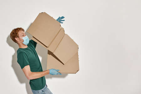 Courier in protective mask and gloves cathing falling pizzaの写真素材