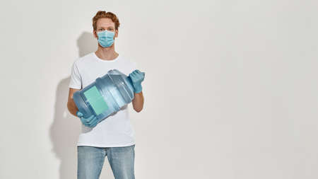 Horizontal picture of a young deliveryman holding big bottle of water