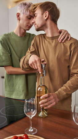 Same-sex male pair uncorking wine bottle