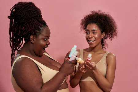 Young mulatto female shows to her friend new line of care productsの写真素材