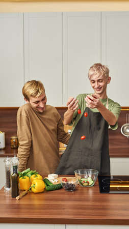 Happy homosexual male couple laughing in kitchenの写真素材
