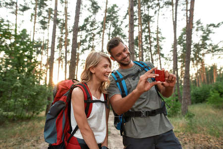 Smiling young man and woman looking into smartphone