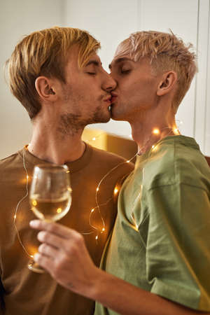 Portrait of male couple kissing holding sparkling garlandの写真素材
