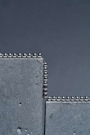 Studio shot of silver metal ball necklace on concrete elements isolated over gray backgroundの写真素材