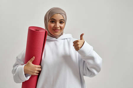 Portrait of happy young arabian woman holding sport matの写真素材
