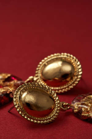Close up shot of epoxy resin golden earrings isolated over red backgroundの写真素材