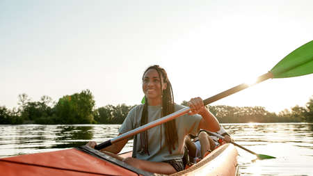 Active young woman smiling, enjoying a day kayaking together with her boyfriend in a lake on a late summer afternoonの写真素材