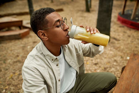 Cheerful young african american man drinking juiceの写真素材