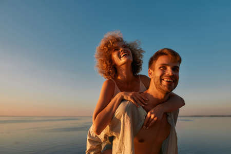 Portrait of happy man holding girlfriend on his backの写真素材