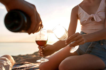 Young couple filling glasses with red wine during date