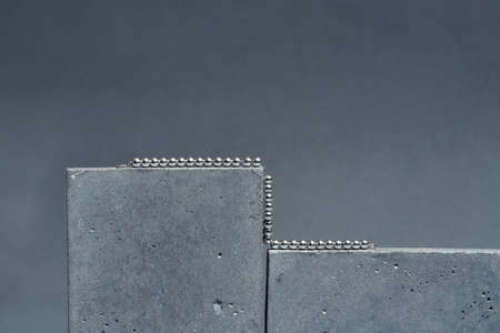 Studio shot of silver metal ball necklace on concrete elements isolated over gray backgroundの写真素材