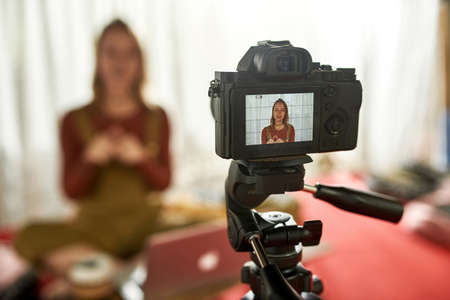 Young woman sitting in lotus pose and telling something on camera
