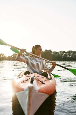 Happy young lady walking by kayak together with her friend on a summer dayの写真素材