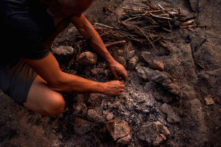 Close up shot of male hands making fire in the wild at sunsetの写真素材