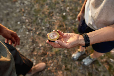 Close up of female hand holding a compass, guided by the area while hiking together with her boyfriend in forestの写真素材