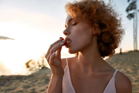 Portrait of redhead young caucasian girl licking strawberryの写真素材