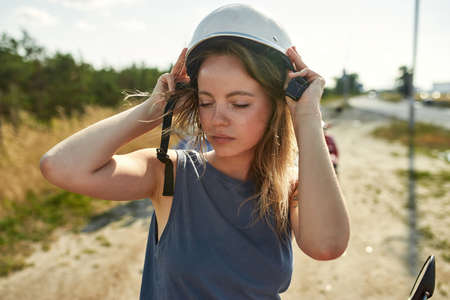 Portrait of young caucasian woman putting on helmetの写真素材