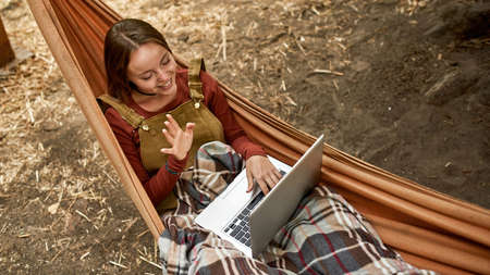 young woman is having a video call while lying in a hammockの写真素材