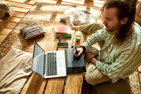 Top view on a man drawing in house on a treeの写真素材