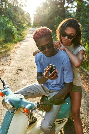 Happy african american man and woman on scooterの写真素材