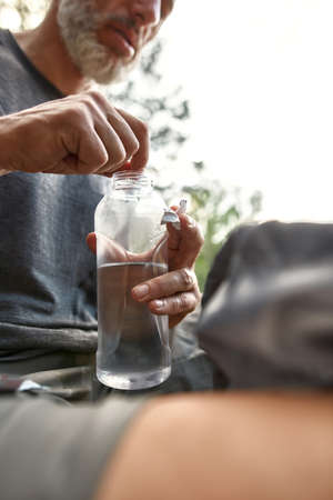 Caucasian man throwing pill for distillation in bottleの写真素材