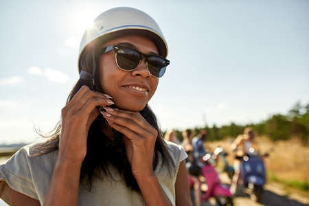 Smiling young african american girl putting on helmetの写真素材