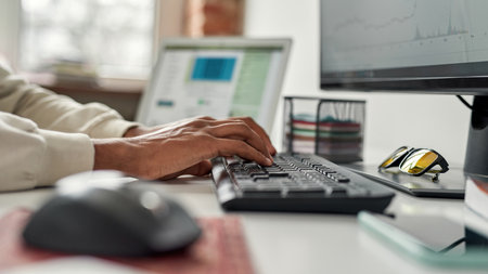 Closeup of hands of male trader typing on keyboard, working on a pc, using online software while trading from homeの写真素材