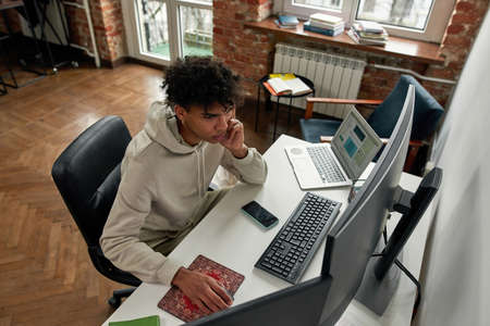 High angle view of concentrated young man trading on stock exchange market while sitting in living...