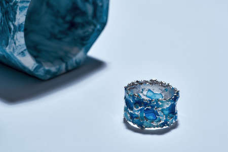 Closeup shot of a ring made of silver metal with blue enamel and industrial blue marble concrete element isolated over light backgroundの写真素材