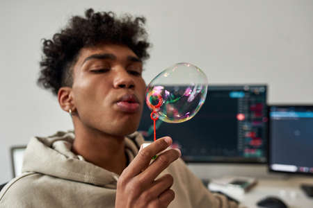 Ethnic man blow soap bubbles relax at home