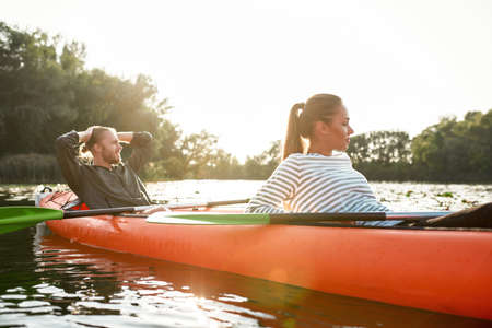 Relaxed young caucasian couple resting while boating together on river on weekendの写真素材