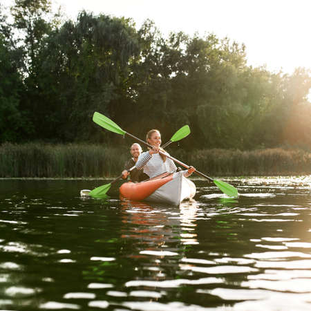 Adventurous young caucasian couple kayaking on river with trees in the backgroundの写真素材