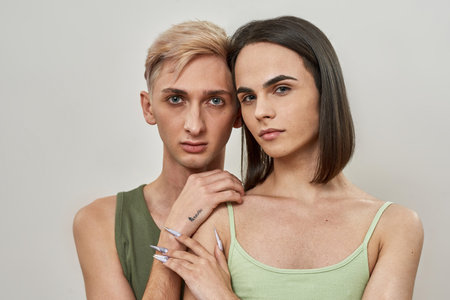 Portrait of couple of two young transgenders looking at camera, posing together isolated over light backgroundの写真素材