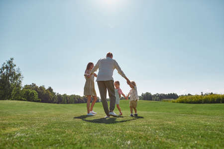 Happy family enjoying leisure activity, spending time together with two little kids, boy and girl in green park on a summer dayの写真素材