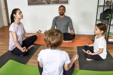Family with teen kids meditate together at homeの写真素材