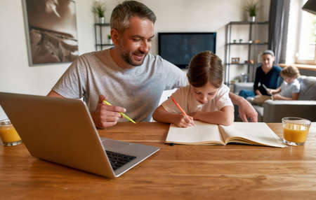 Caring father and small daughter do homework in notebookの写真素材