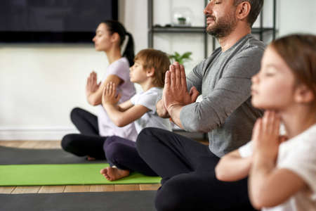 Crop of family with kids practice yoga meditateの写真素材