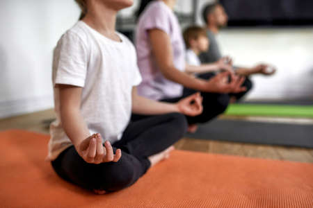 Crop of family with kids meditate at home togetherの写真素材