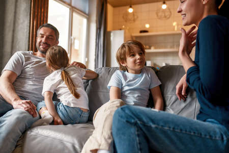 Little happy kids talk with loving parents at homeの写真素材